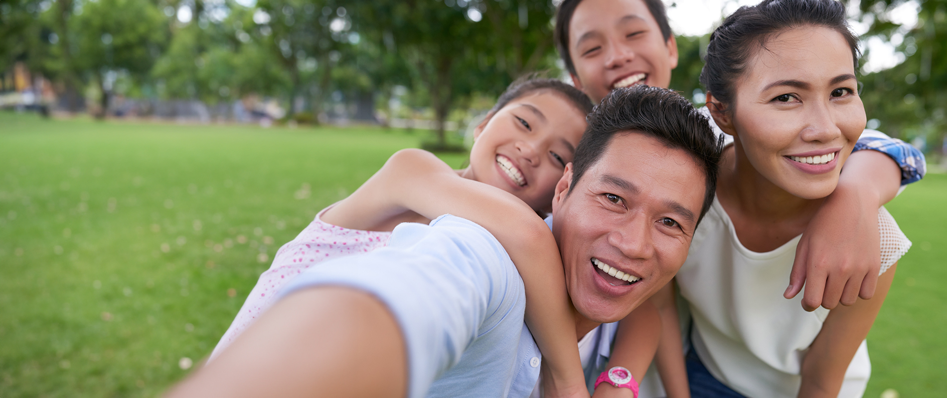 The image depicts a group of people outdoors, with a man taking a selfie with them while they pose for the camera.