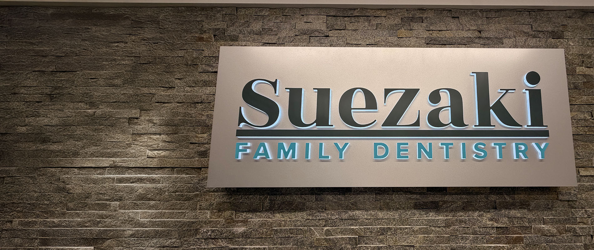The image shows a sign with the text SUEZAKI FAMILY DENTISTRY prominently displayed, indicating the name of a dental practice.