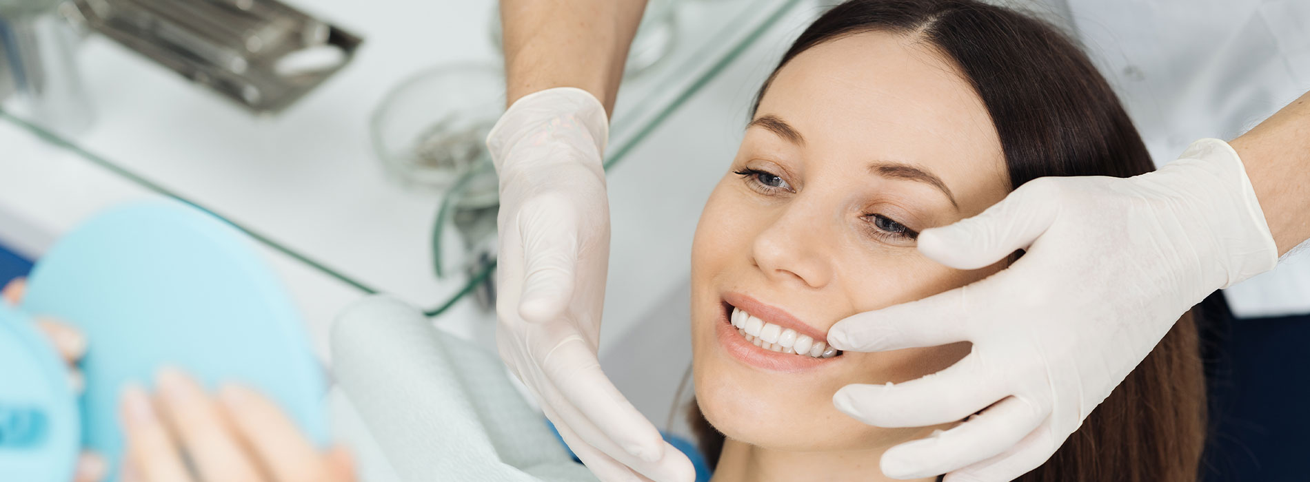A woman receiving a facial treatment with a professional using a blue mask.