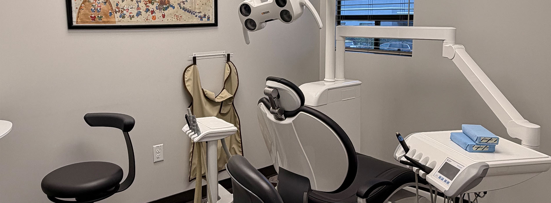 The image shows a dental office interior with a modern dental chair, equipment, and an open door revealing another room.