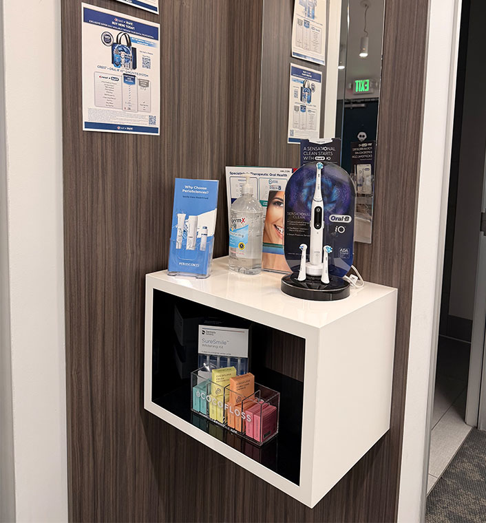 The image shows a display case with various items inside, placed against a wall with a mirror reflection, set within an interior space that appears to be a professional office environment.