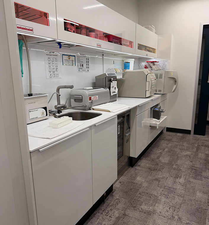 The image depicts a clean, well-equipped kitchen with white cabinets, stainless steel appliances, and various items on the countertop.