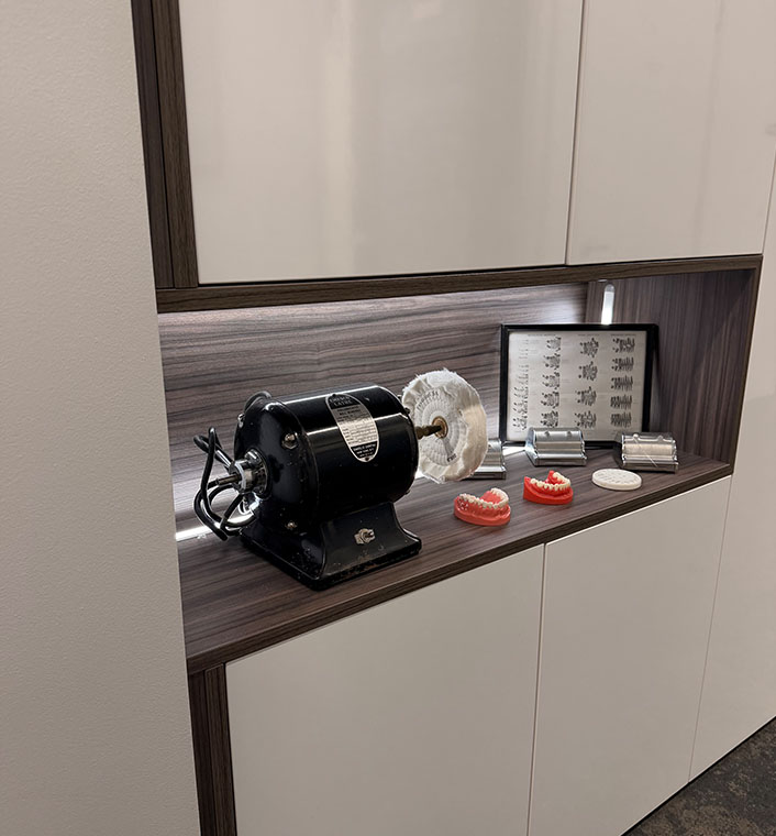 The image shows a modern kitchenette with a wooden countertop, featuring a black vintage-style rotary mixer, red toothbrushes, and other kitchen items on display.