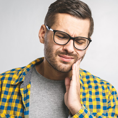 The image shows a man wearing glasses with his hand on his chin, appearing to be deep in thought or contemplation.
