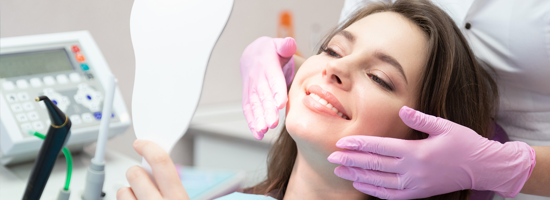 A woman receiving dental care with a hygienist using a mirror to inspect her teeth.