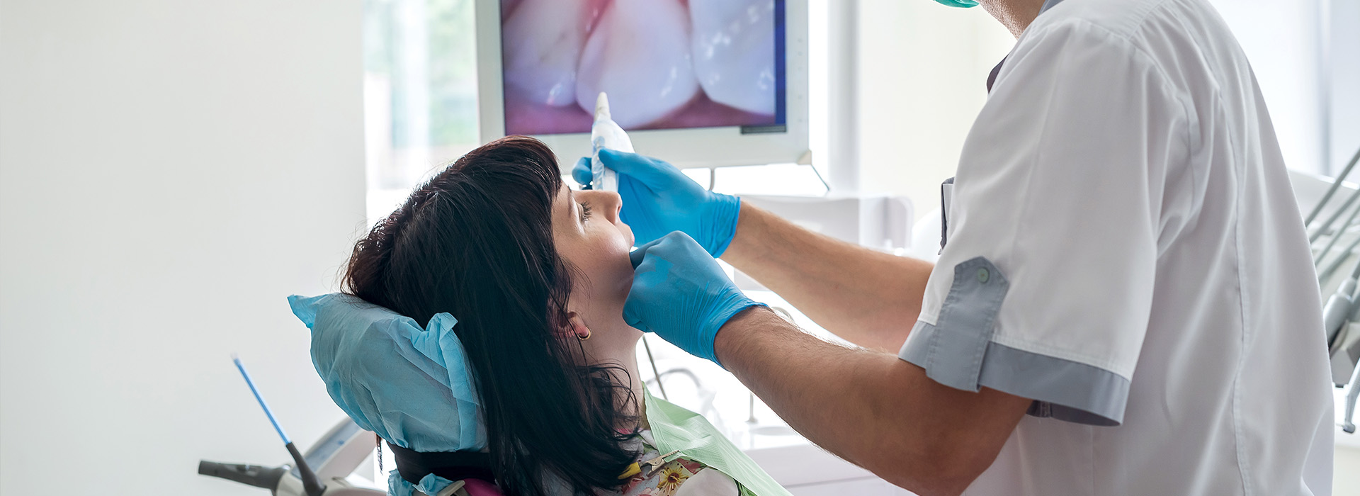 An image of a dental professional performing a procedure on a patient s mouth with medical equipment.