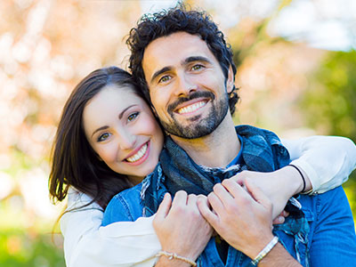 The image shows a man and a woman embracing each other with smiles on their faces.