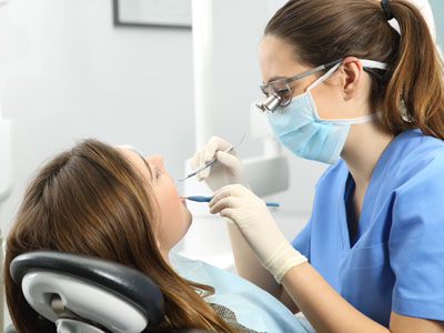 A dental hygienist providing oral care to a patient in a dental office setting.
