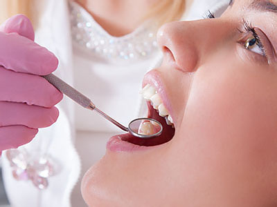 The image shows a person receiving dental care from a professional, with a focus on the dental tools being used and the interaction between the patient and the dentist.