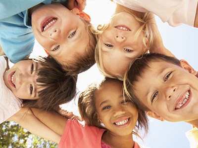 The image shows a group of children posing together with smiles on their faces, taken from an overhead angle.